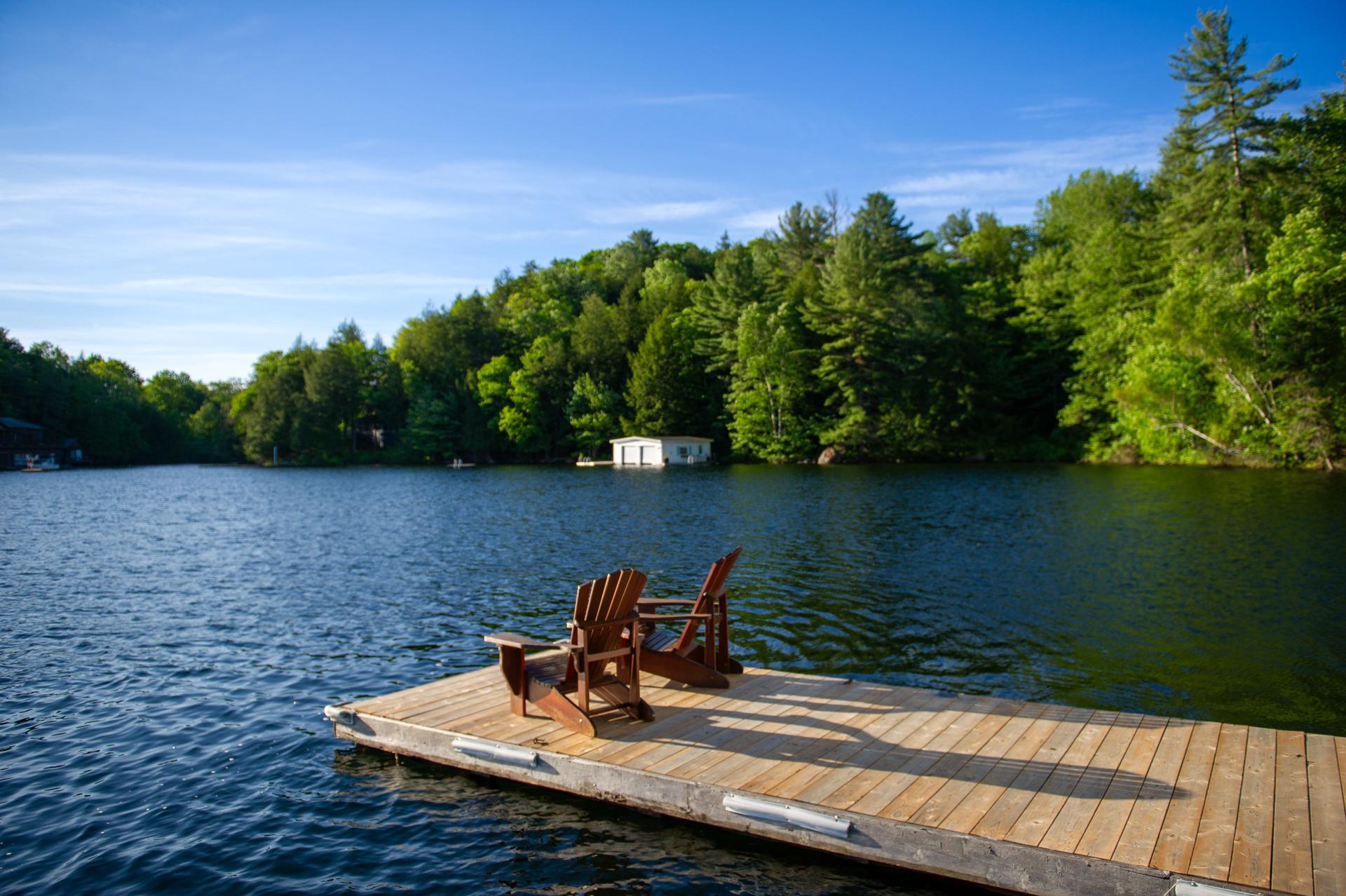 Two Adirondack chairs on a wooden dock on a summer morning